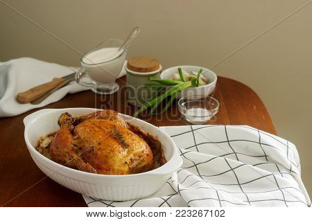 Baked chicken with herbs and garlic, served with sour cream sauce. Rustic style, selective focus.