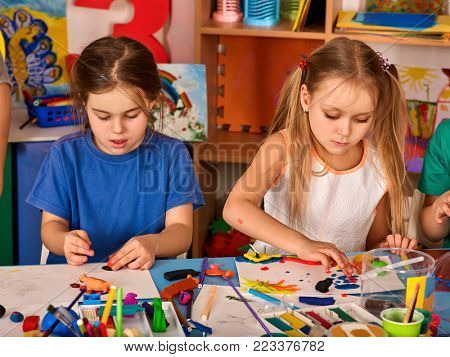 Child dough play in school. Plasticine for children. Mold from plasticine in kindergarten. Kids knead modeling clay with hands in preschool. Children knead modeling clay who is faster.