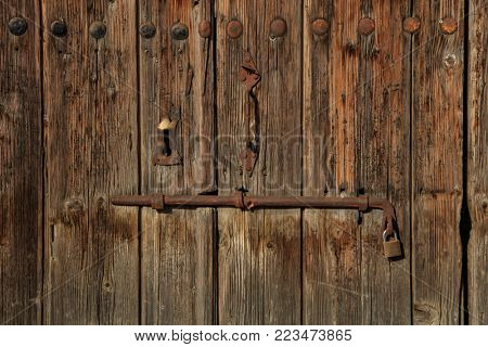 Wooden brown door. Timeworn blank, banner, background with rusty latch and padlock. Closeup, details
