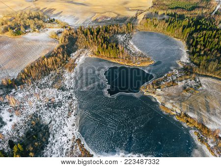 Aerial Drone Photograph of a Partly Frozen Lake Surrounded with Beautiful Winter Colors of the Fields and Forest