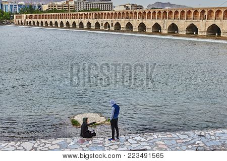 Isfahan, Iran - April 24, 2017: Romantic Date of the Iranian couple on the embankment of the Zayandeh river near the stone bridge Allahverdi Khan.