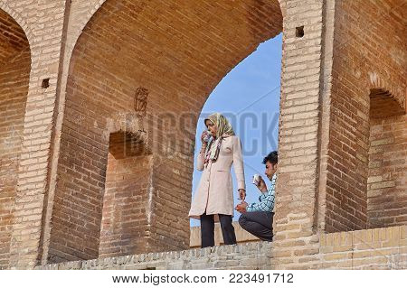 Isfahan, Iran - April 24, 2017: A young couple arranged a picnic on the ancient stone bridge Allahverdi Khan.