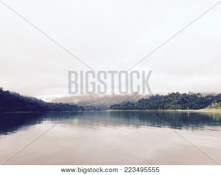 Beautiful lake and colorfuls forest in autumn cloud. Beautiful forest of colorful autumn trees reflecting in calm lake in Ratchapapla Dam (South of Thailand).