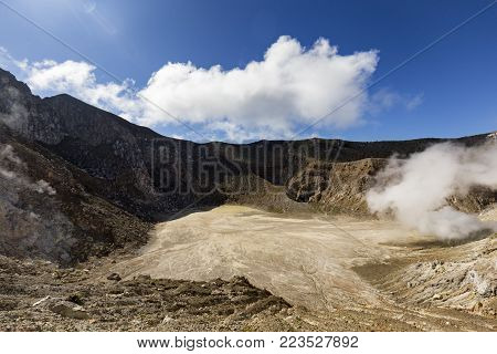 The caldera on Mount Egon with a small acidic lake and sulphuric gasses coming from within the volcano.