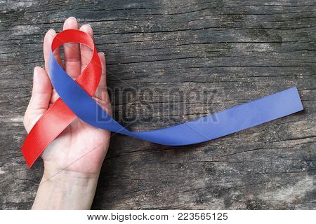 Red And Blue Ribbon Awareness On Woman Human Hand Aged Wood For Congenital Heart Defects Disease