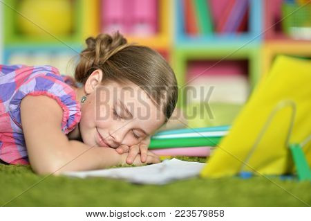 Portrait of tired schoolgirl sleeping on exercise book