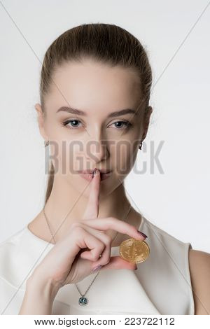 Young beautiful girl with gold bitcoin in hand on white background