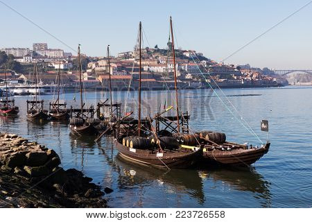 PORTO, PORTUGAL - JANUARY 18,2018: Boats carrying barrels of porto wine seen docking at river bank. Panorama View on Porto, Duoro River, Ribeira District.
