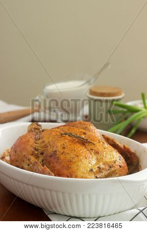 Baked chicken with herbs and garlic, served with sour cream sauce. Rustic style, selective focus.