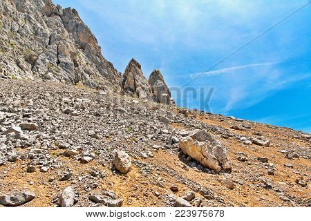 Slope With A Talus Of Stones In Mountains. Sunny Summer Day, The Blue Sky With Traces From Planes