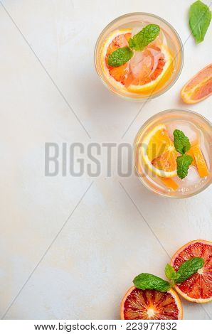 Cold refreshing drink with blood orange slices in a glass on a white concrete background. Top view, flat lay, copy space.