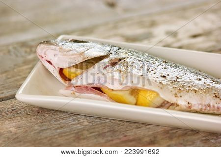 Lemons inside fish closeup. Gutted raw fish with lemons inside.