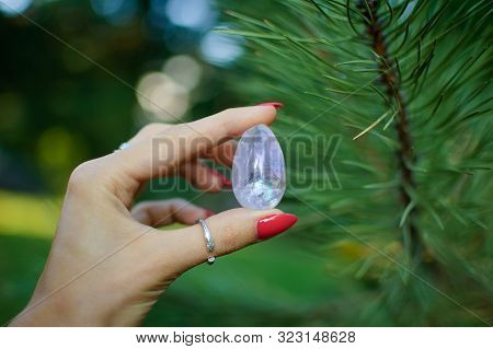 Female Hand With Transparent Amethyst Quartz Yoni Egg For Vumfit, Imbuilding Or Meditation. Shining 