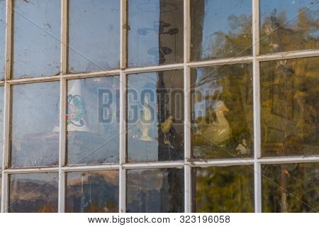 Old Decorative Objects Behind The Window Of An Abandoned Gas Station In Maryhill, Washington, Usa