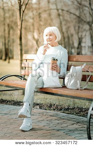 Elderly Missis Relishing Of Coffee And Cookie In The Parkland