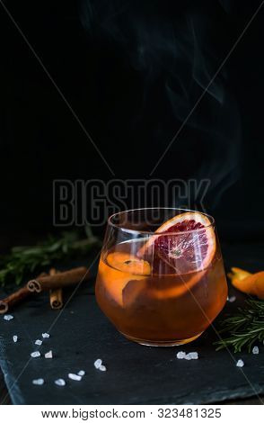Negroni Cocktail On Black Background Served With A Slice Of Orange And Rosemary. Old Cocktail Classi