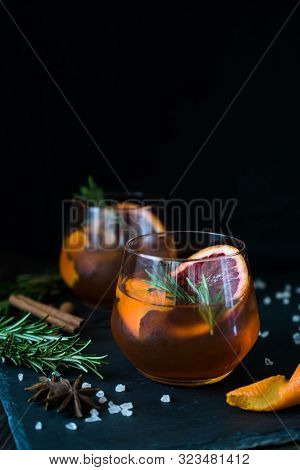 Negroni Cocktail On Black Background Served With A Slice Of Orange And Rosemary. Old Cocktail Classi