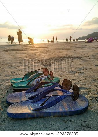 Andaman, India - Feb 2017: Pair Of Slippers With Sun Glasses Placed On Them In A Beach With A Backdr