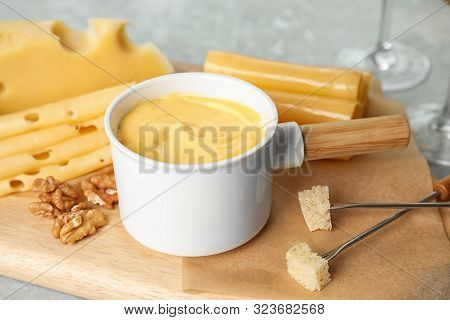 Pot Of Tasty Cheese Fondue Served On Cutting Board