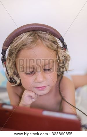 Little Blond Child Streaming Online On Tablet With Headset. Favorite Video Game. Overstimulated Chil