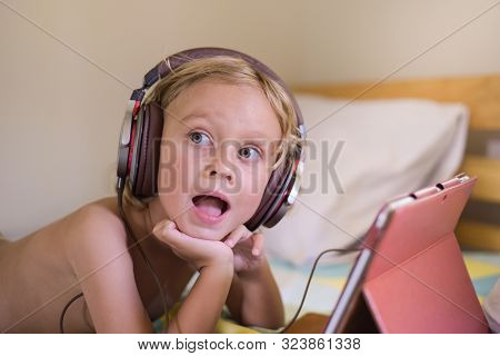 Surprised Little Blond Child Streaming Online On Tablet With Headset.favorite Video Game.overstimula