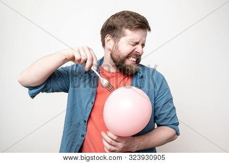 Bearded Man Is About To Burst A Balloon With A Fork And Bared His Teeth In Fear. Fun Or Stress Conce