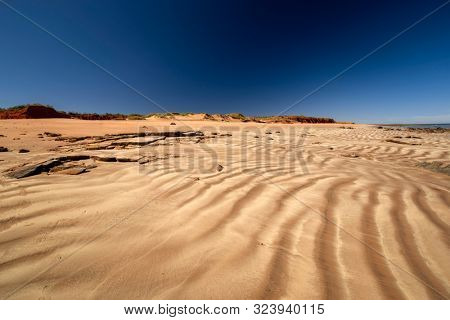 Western Australia - coast line at Dampier Peninsula with rippled sand dune and hill in the background in morning light 