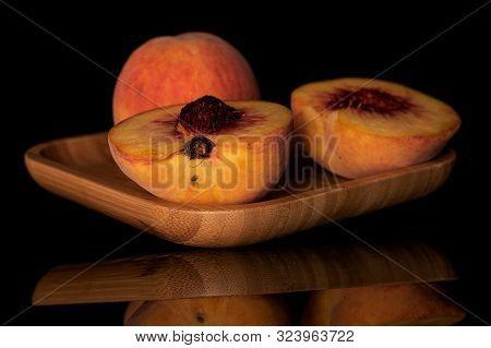 Group Of One Whole Two Halves Of Fresh Fuzzy Peach On Wooden Square Plate Isolated On Black Glass