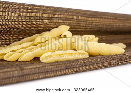 Lot Of Whole Uncooked Pasta Cavatelli With Brown Textil Cloth Isolated On White Background
