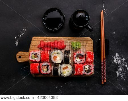 Sushi maki set composition with ginger, wasabi and soy sauce serves on wooden tablet and shooting from above. Traditional japanese meal rool and chopstick