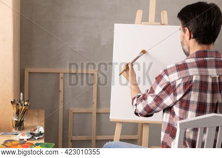 Male artist working on painting. Man artist painter in creative studio as art concept