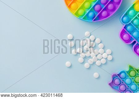 Sensory Toy Poppit And Pills On Blue Background As Medication For Adhd Or Autism. Colorful Silicone 