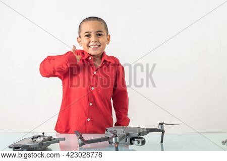 Cute Boy With Skinhead Hairstyle In A Red Long-sleeve Shirt Is Assembling A Drone 
On A Clear Glass 