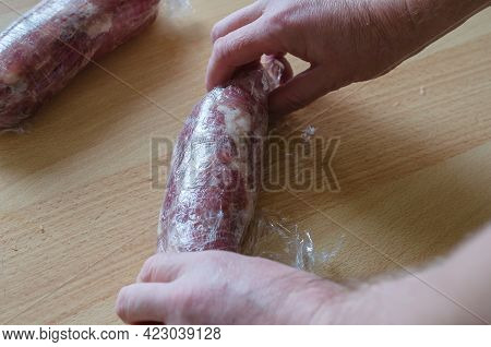 Step By Step Preparation Of Homemade Chopped Ham. Step 10: A Man's Hands Are Twisting A Portion Of M