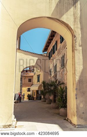 Lovran Croatia - 05 June 2021: Narrow Street Of Ancient Old Town With Arc, Vintage Buildings And Pal