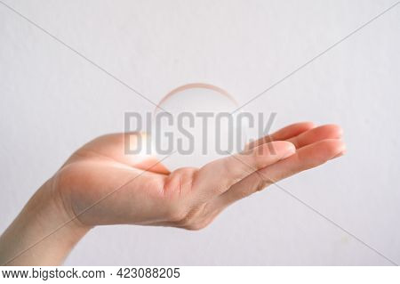 Close Up Of Someone Hand Holding A Clear Transparent Crystal Ball. The Use Of Crystal Balls To Predi