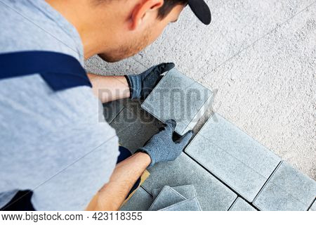 Worker lining paving slabs path