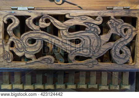 A Dragon Carved From Wood With An Ornate Image On The Keyboard Cover Of The Medieval Folk Music Inst