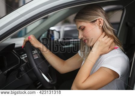 Young Woman Suffering From Neck Whiplash, Sitting In Drivers Seat Of Her Car