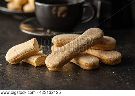 Italian cookie savoiardi. Sweet biscuits. Sponge cookies tiramisu on black table.
