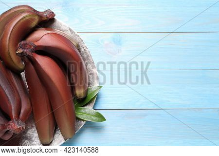Tasty Red Baby Bananas On Light Blue Wooden Table, Top View. Space For Text