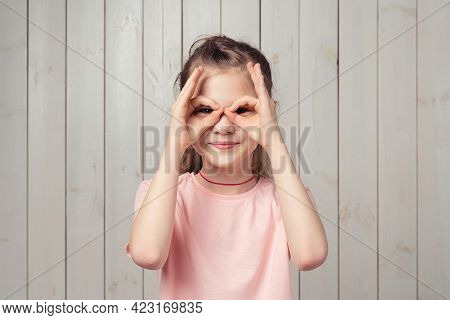 Fun Little Girl 9-11 Years Old Holding Fingers Near Eyes Like Glasses: Mask Like Superhero, Standing