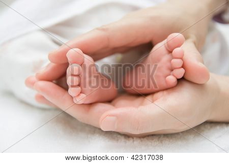 Újszülött baba lábát egy női kéz