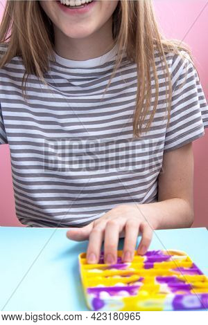 Child In Casual Clothes Plays With Trend Bright Multicolored Antistress Toy Pop It. Poppit New Fidge