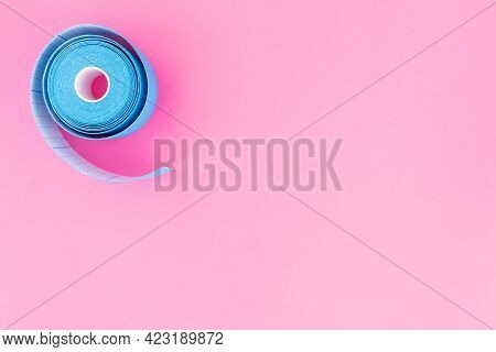 Blue Roll Of Kinesiology Tape On Pink Background With Copy Space, Flat Lay. Recovery, Anti-aging Pro