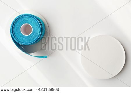 Blue Roll Of Kinesiology Tape On White Background With Shadows And Podiums, Flat Lay. Recovery, Anti