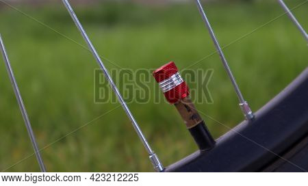 Bicycle Red Nipple. Detail Of A Used Bicycle Rim With Valve Stem And Cover. Mountain Bike Tire. Bicy