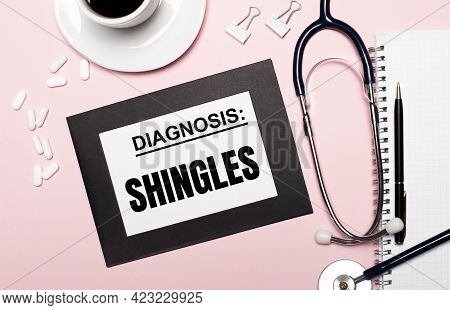 On A Light Pink Background, A Notebook With A Pen, Stethoscope, White Pills, Paper Clips And A Sheet