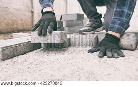 Worker lining paving slabs path