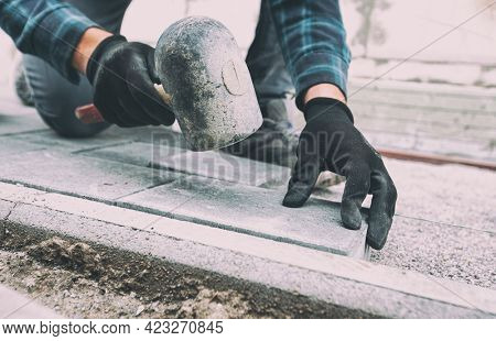 Worker lining paving slabs path